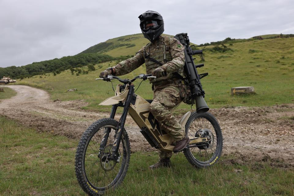Image the UK Armed Forces, seen here demonstrating the Stealth H-52 electric bike Lulworth Range. Also seen slung over their shoulder is a Carl Gustaf Mk 4 rocket launcher. <em>Crown Copyright</em>