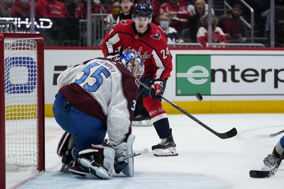 Colorado Avalanche goaltender Darcy Kuemper (35) deflects a shot as Washington Capitals center Connor McMichael (24) stands nearby during the first period of an NHL hockey game Tuesday, Oct. 19, 2021, in Washington. (AP Photo/Alex Brandon)