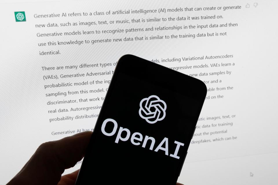 The OpenAI logo is seen on a mobile phone in front of a computer screen displaying output from ChatGPT, Tuesday, March 21 in Boston. (Photo: Michael Dwyer/Associated Press/File)