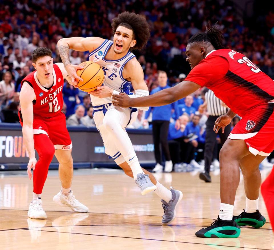 Duke’s Proctor drives between NC State defenders Michael O’Connell (12) and DJ Burns in first half action from the NCAA Elite 8 in Dallas, Sunday, March 31, 2024.