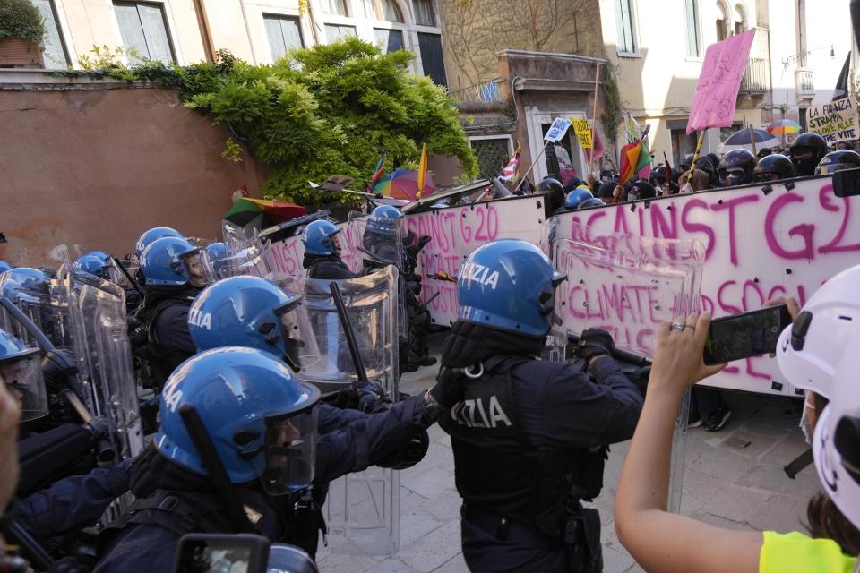 Italian Policemen in riot gears clash with demonstrators during a protest against the G20 Economy and Finance ministers and Central bank governors' meeting in Venice, Italy, Saturday, July 10, 2021. (AP Photo/Luca Bruno)