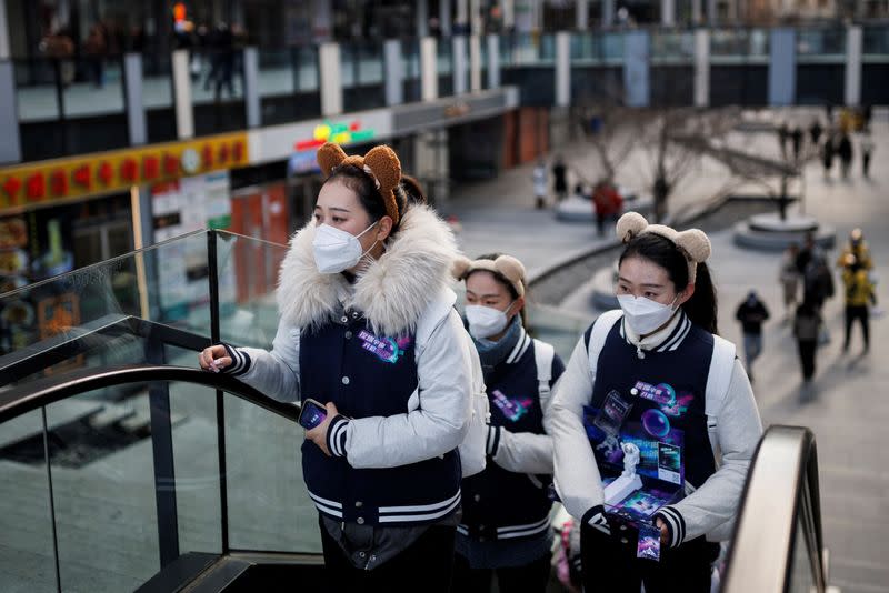 Women carry promotion material in a shopping district as China returns to work despite continuing coronavirus disease (COVID-19) outbreaks in Beijing