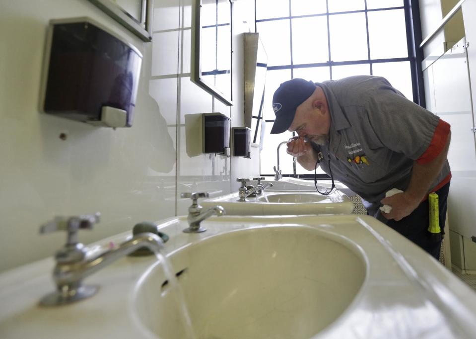 FILE - In this Jan. 13, 2014, file photo, Al Jones of the West Virginia department of General Services tests the water as he flushes the faucet and opens a rest room on the first floor of the State Capitol in Charleston, W.Va. A federal health official on Wednesday, Feb. 5, 2014 said that West Virginians can use tap water however they choose after last month's chemical spill contaminated it for days. Still, public skepticism remains over its safety and some local doctors are advising some of their patients not to ingest it. (AP Photo/Steve Helber)