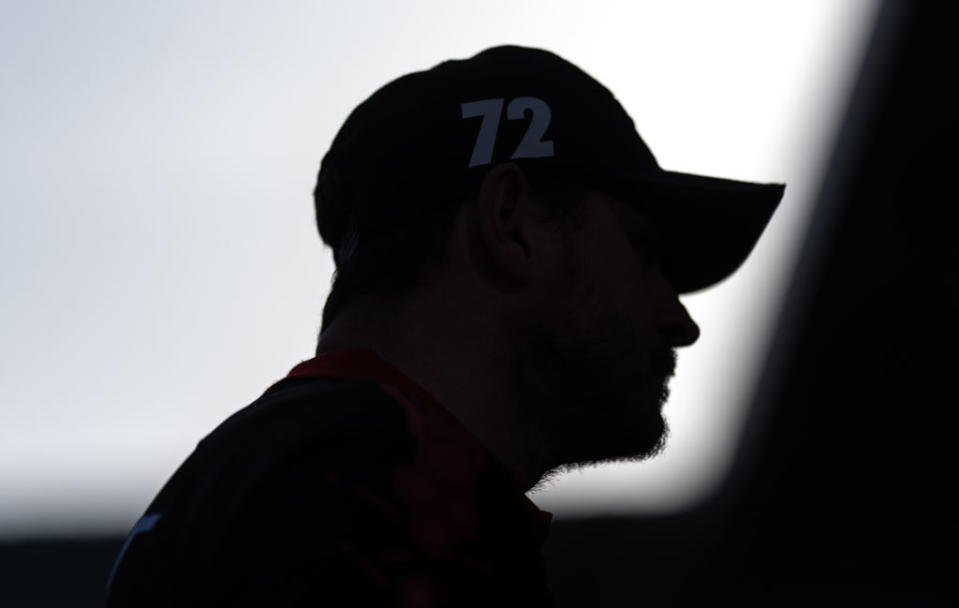 Silhouette of an unidentifiable person with a cap labeled '72' amidst a dimly lit setting