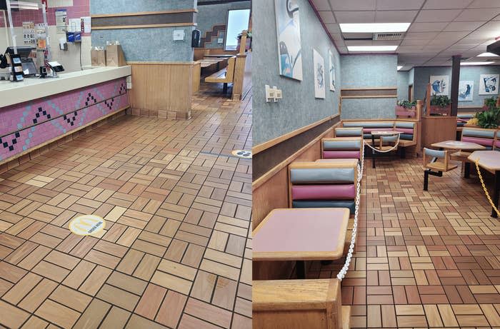 Empty fast food restaurant interior with tiled floor, booths, and social distancing markers on the floor. No people are present