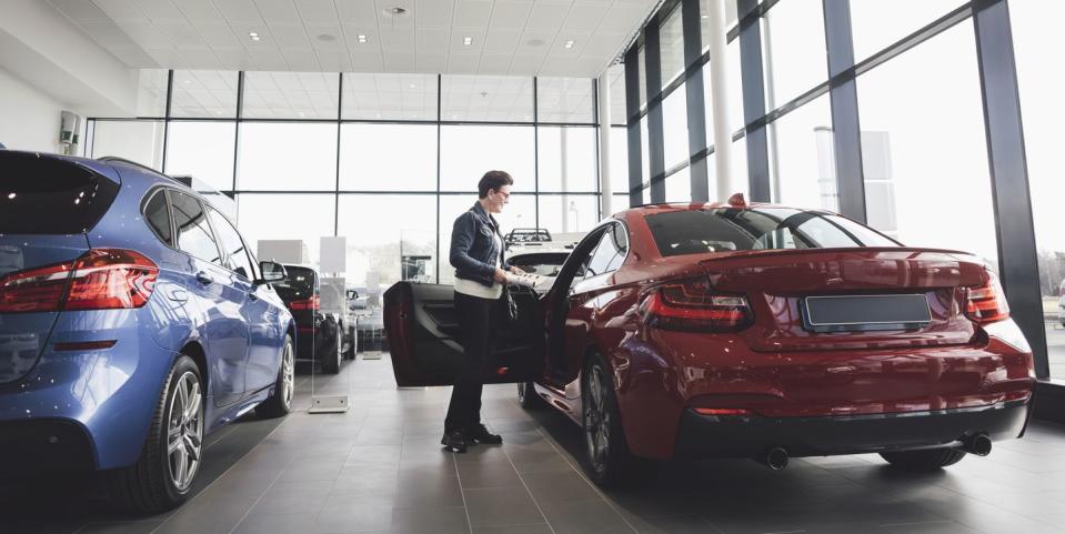 senior woman looking inside car in showroom