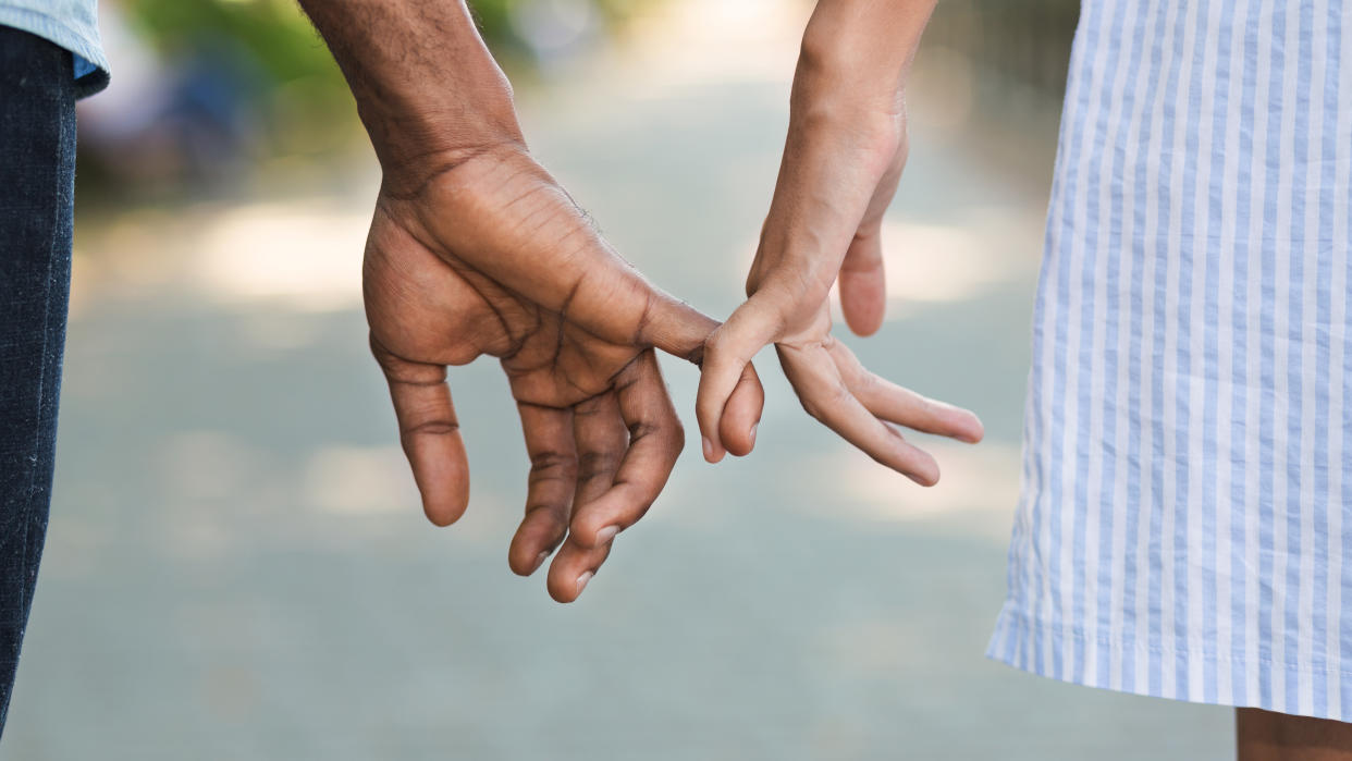 Loving couple holding little fingers while walking in park