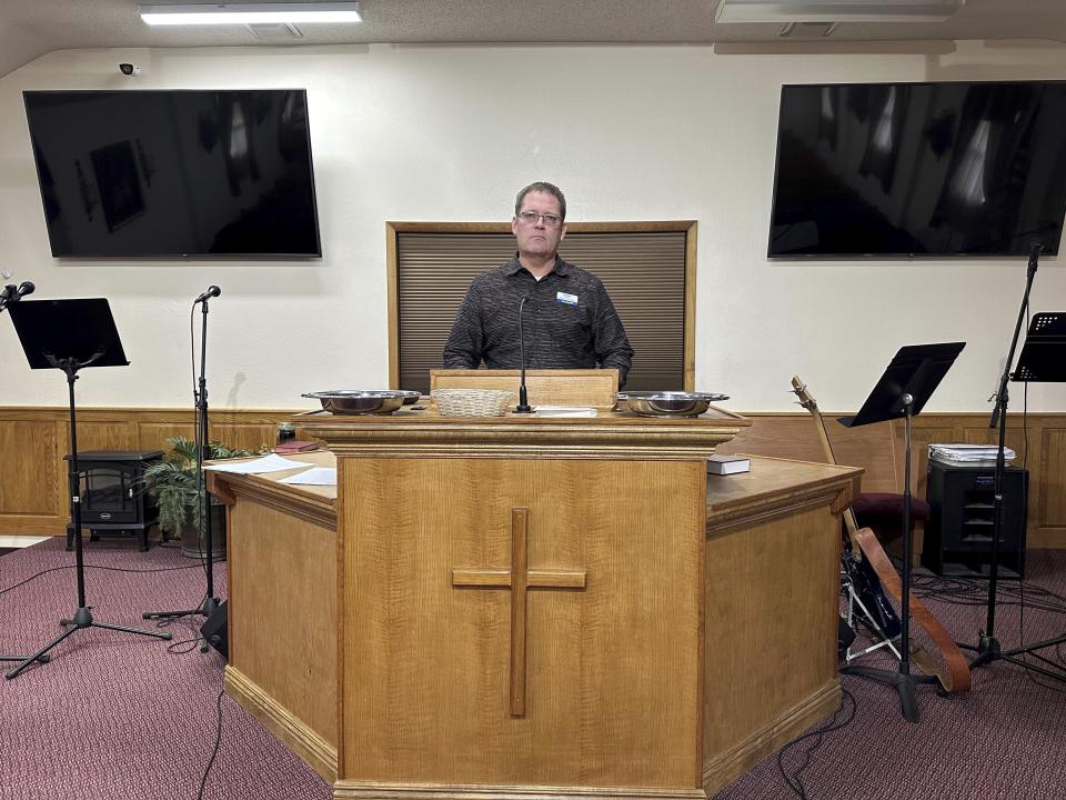 Pastor Kenny Batson stands at the pulpit of Grace Fellowship Church on Nov. 16, 2023, in El Dorado Springs, Mo. Batson was convicted of a series of crimes in the 1990s but became a Christian pastor after being released from prison. He was pardoned by Missouri Gov. Mike Parson. (AP Photo/David A.Lieb)