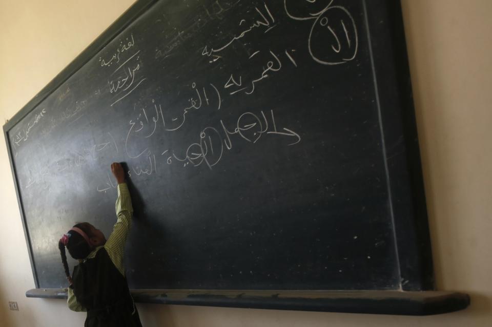 A girl writes on the blackboard on the first day of her new school year at a government school in Giza