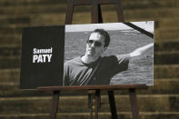 The portrait of slain teacher Samuel Paty with a black ribbon is displayed Tuesday, Oct.20, 2020 on the steps of the National Assembly in Paris. A memorial march will be held Tuesday evening near Paris in homage to the history teacher who was beheaded last week, while French police said 16 people remain in custody as part of the investigation into the attack. (AP Photo/Lewis Joly)