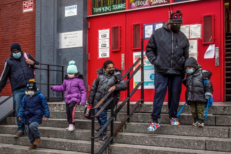 Children and their guardians wearing masks because of COVID-19 pandemic, leave P.S. 64 in the East Village neighborhood of Manhattan, Dec. 21, 2021, in New York.