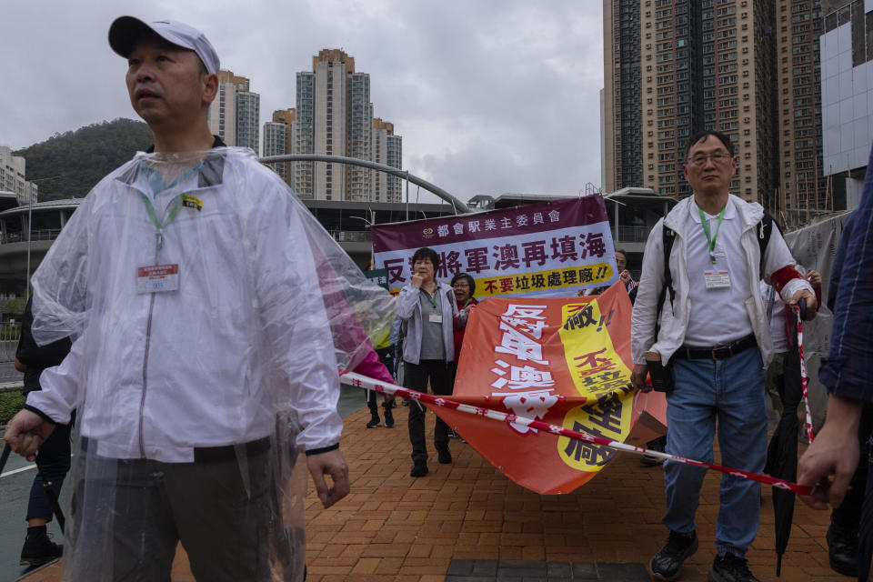 Protesters walk within a cordon line wearing number tags during a rally in Hong Kong, Sunday, March 26, 2023. Dozens of people on Sunday joined Hong Kong's first authorized demonstration against the government since the lifting of major COVID-19 restrictions under unprecedentedly strict rules, including wearing a numbered badge around their necks. (AP Photo/Louise Delmotte)