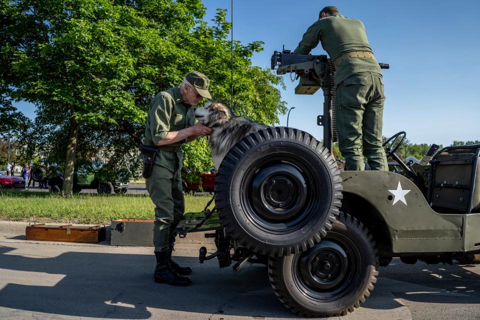 Rich Margittay, left, talks with his dog Cheyenne as she sits in his 1949 Willys Jeep as Garret Wasko of Taylor works to add a .30 caliber Browning machine gun to the vehicle before the start of the 97th annual Memorial Day parade along Michigan Avenue in Dearborn on Monday, May 29, 2023.