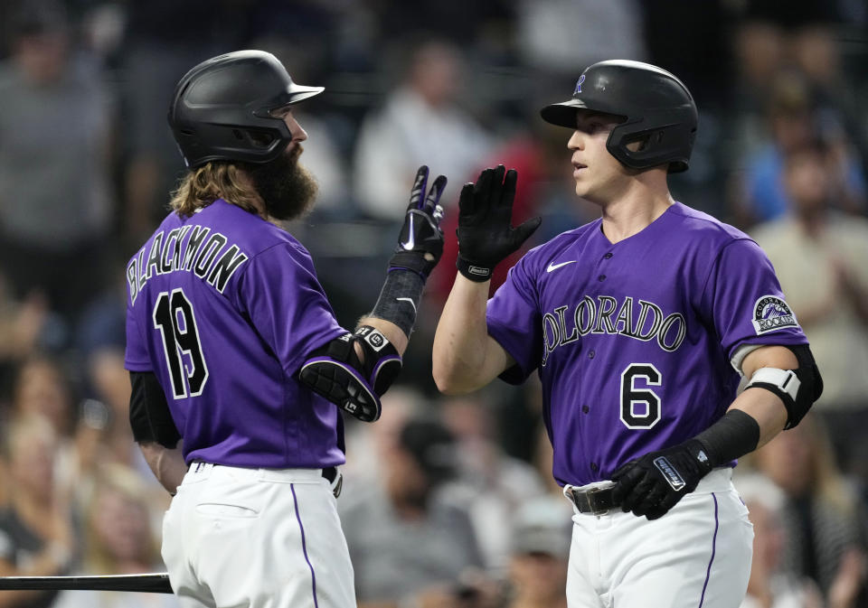 Colorado Rockies' Charlie Blackmon, left, congratulates Brian Serven who crosses home plate after hitting a solo home run off Arizona Diamondbacks starting pitcher Zach Davies in the fifth inning of a baseball game Friday, Aug. 12, 2022, in Denver. (AP Photo/David Zalubowski)