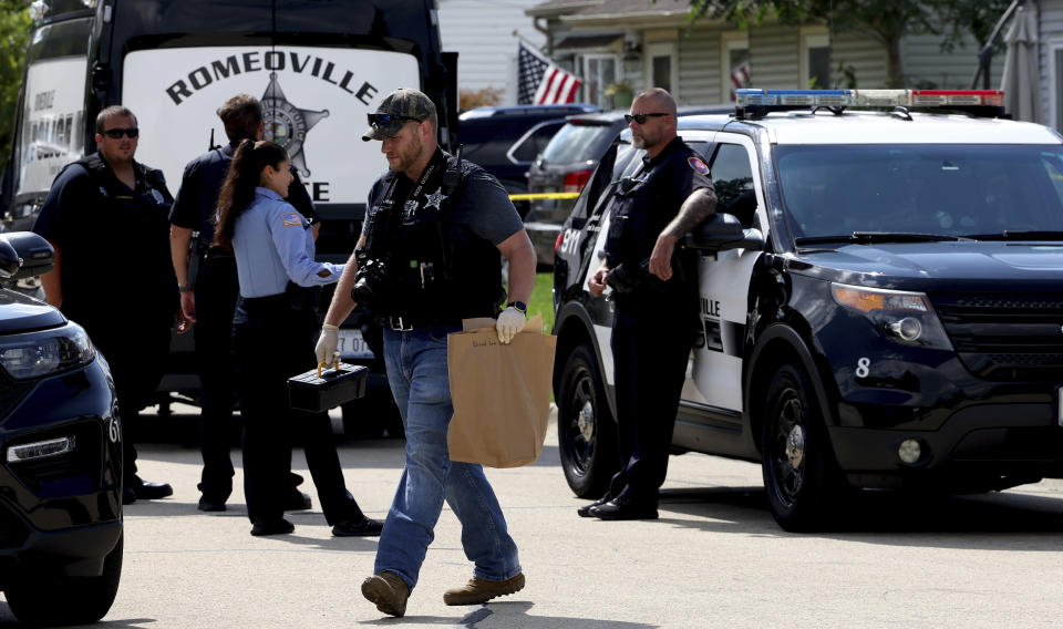 FILE - A Romeoville Police officer carries out a brown bagged marked with the words, "Drywall from hallway" from inside of the home where four people were shot to death on Monday, Sept. 18, 2023, in Romeoville Ill. The suspect in the shooting deaths of the suburban Chicago family was in a relationship with one of the four people slain and his girlfriend allegedly helped plan the killings, police investigators said, Thursday, Dec. 7. (Stacey Wescott /Chicago Tribune via AP)