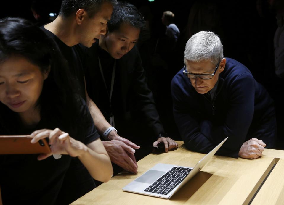 Apple CEO Tim Cook (R) views the MacBook Pro in the demo room after an Apple media event in Cupertino, California, U.S. REUTERS/Beck Diefenbach