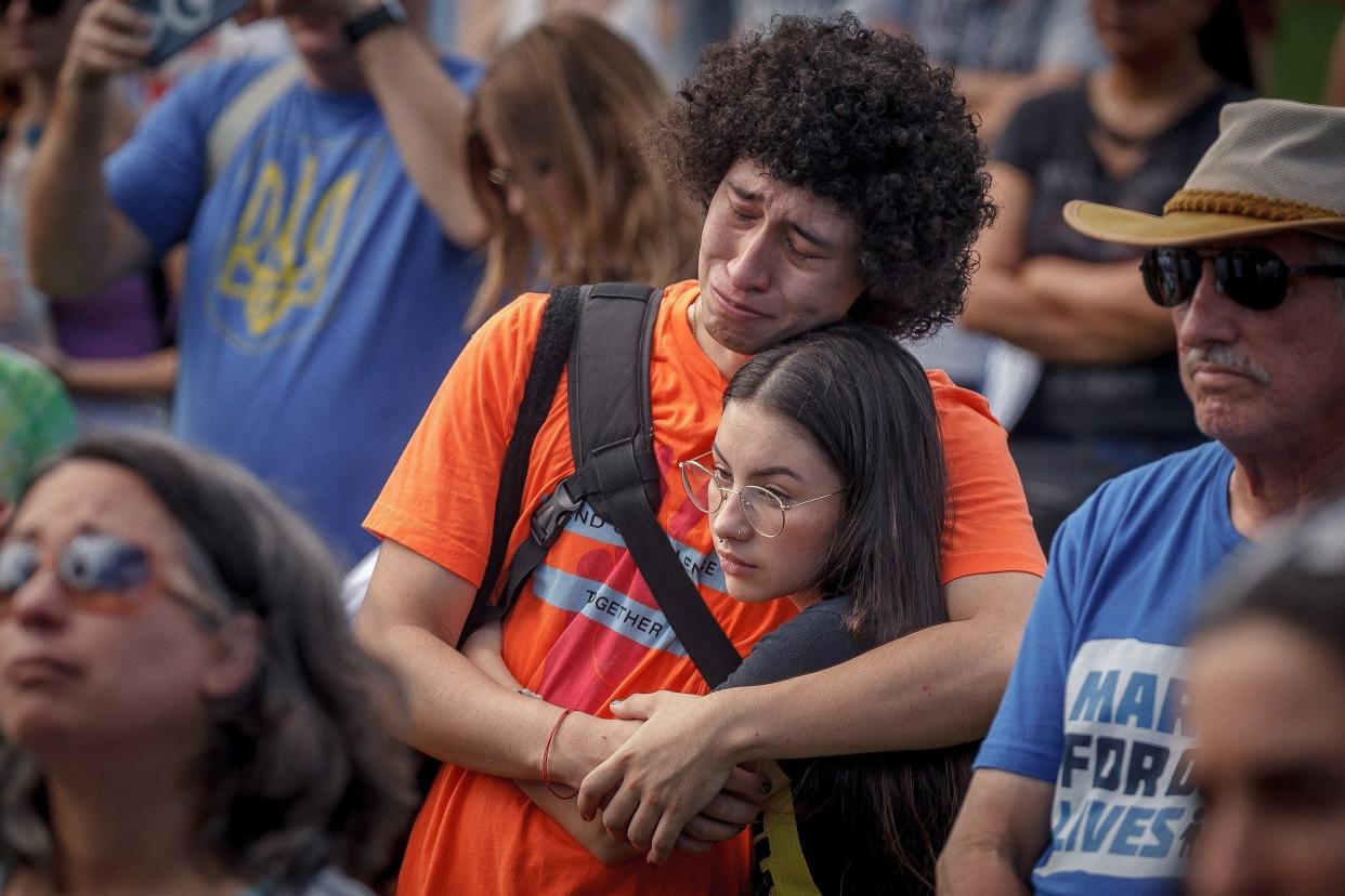 Carlos Rodriguez of Parkland weeps in the arms of Camila Cortes of Coral Springs as a speaker recalls the Marjory Stoneman Douglas High School shooting during a "March for our Lives" event at Pine Trails Park in Parkland in June 2022. Rodriguez and Cortes graduated from the school in 2019.