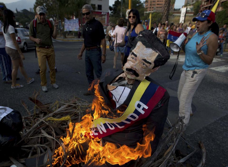 ARCHIVO - Ciudadanos opositores queman una figura con la imagen del presidente de Venezuela, Nicolás Maduro, en Caracas, Venezuela, el 20 de abril de 2014. (AP Foto/Fernando Llano, Archivo)