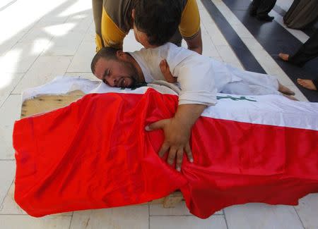 A man mourns on the coffin of Salah al-Wa'ili, a fighter from the Iraqi Shi'ite group Asa'ib Ahl al-Haq, during his funeral in Najaf July 12, 2014. REUTERS/Alaa Al-Marjani