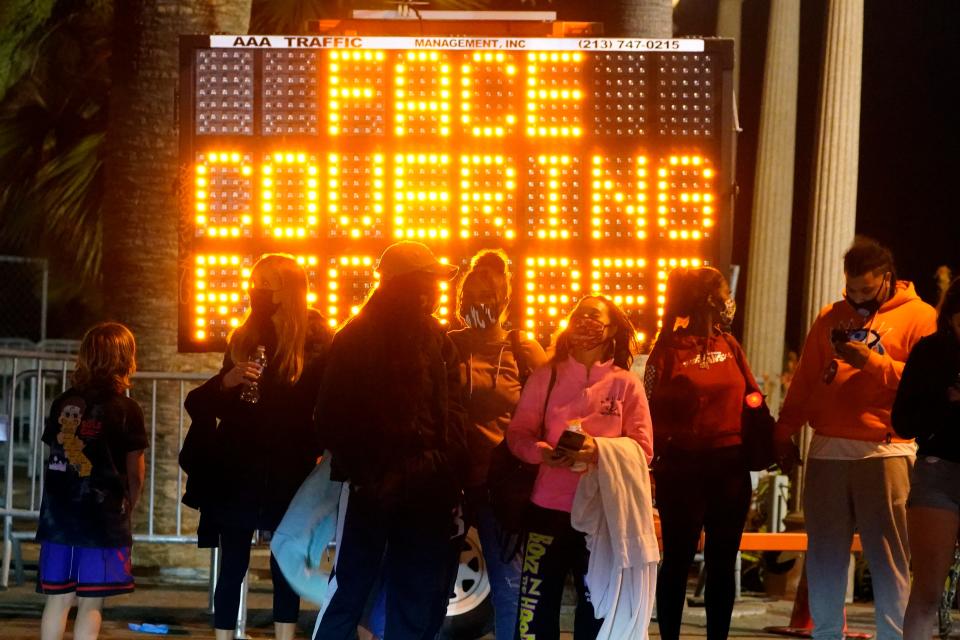 A sign encourages visitors to wear face masks amid the COVID-19 pandemic Friday, Feb. 19, 2021, in Santa Monica, Calif.