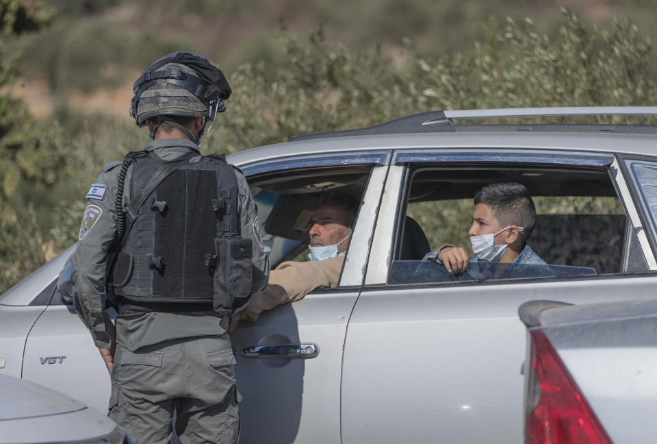 Israeli border police closed the road and blocked activists trying to join Palestinian farmers and help them reach their groves for olive harvest, in the West Bank village of Burqa, East of Ramallah, Friday, Oct. 16, 2020. Palestinians clashed with Israeli border police in the West Bank on Friday during their attempt to reach and harvest their olive groves near a Jewish settlers outpost. (AP Photo/Nasser Nasser)