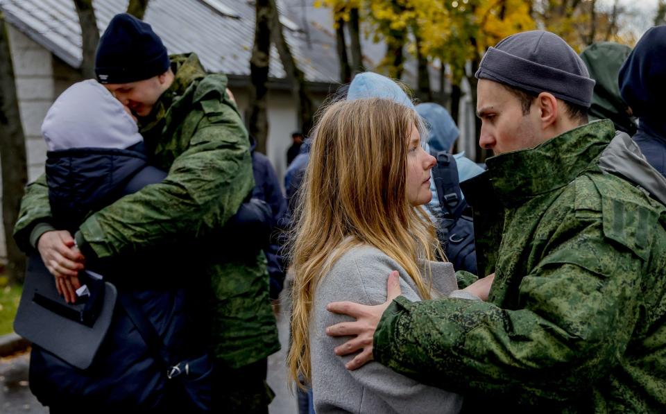 Mobilised men hug and console their loved ones before departing for the front line in October 2022