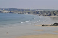 People walk along the normally crowded sands on Tolcarne beach on the north coast of Cornwall, southern England, as the UK continues in lockdown to help curb the spread of the coronavirus, in Newquay, England, Friday April 10, 2020. People are allowed out for personal exercise but public recreation facilities have been closed off due to coronavirus. The highly contagious COVID-19 coronavirus has impacted on nations around the globe, many imposing self isolation and exercising social distancing when people move from their homes. (Ben Birchall / PA via AP)