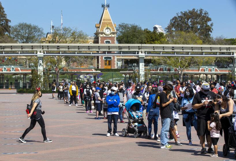 ANAHEIM, CA - March 18: With a view of Disneyland behind them, Disney fans wait in line to attend the debut of Disney California Adventure's "A Touch of Disney" food event at Disney California Adventure Park Thursday, March 18, 2021 in Anaheim, CA. This spans the entire DCA park and allows guests to eat, interact with characters and explore the grounds. A Touch of Disney, the new limited-time ticketed experience at Disney California Adventure Park which has sold out, takes place March 18 through April 19, 2021. (Allen J. Schaben / Los Angeles Times)