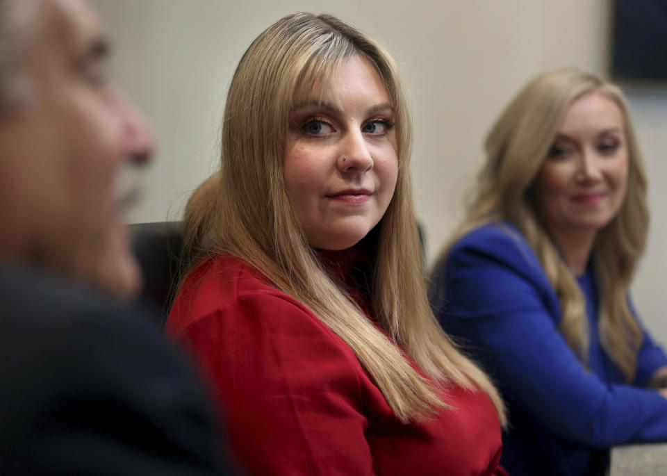 Abigail Zwerner, center, a teacher who was shot at Richneck Elementary School in Newport News, Va., by her 6-year-old student last year, listens as one of her attorneys talks to reporter Peter Dujardin, Wednesday, Jan. 3, 2024, in Virginia Beach, Va. (Stephen M. Katz /The Virginian-Pilot via AP)