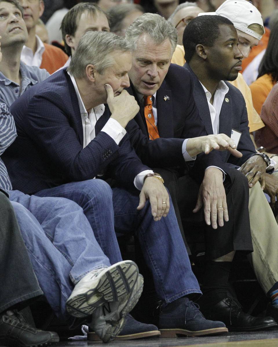 Virginia Gov. Terry McAuliffe, right, talks with writer John Grisham during the first half of an NCAA College basketball game in Charlottesville, Va., Saturday, March 1, 2014. (AP Photo/Steve Helber)