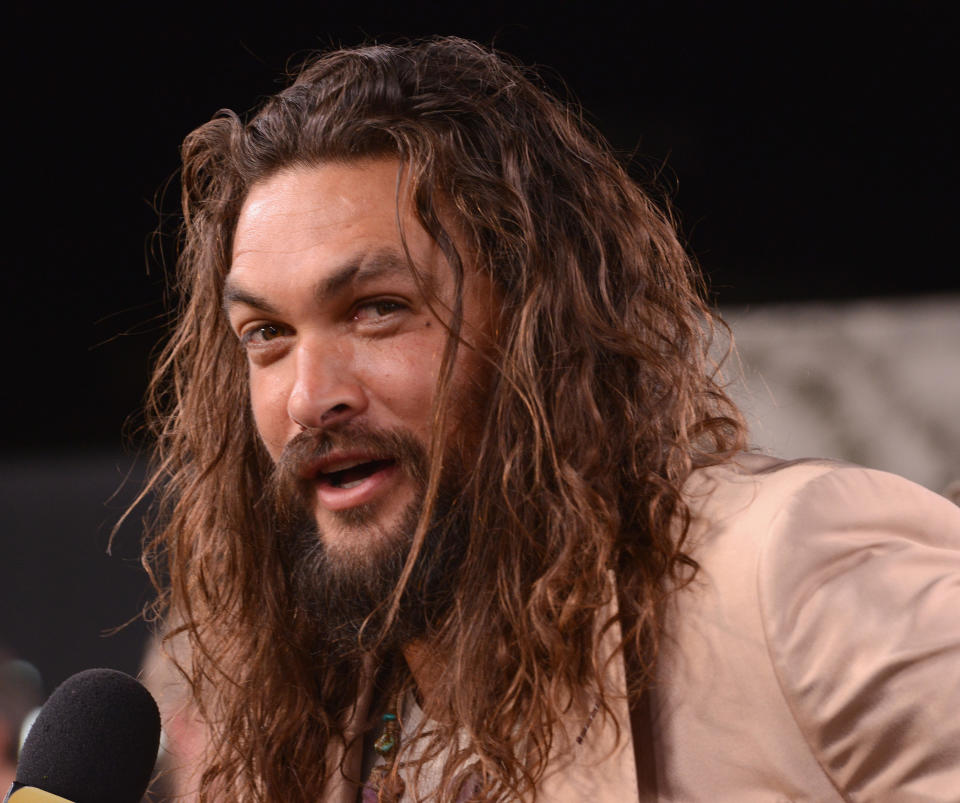 Closeup photo of Jason Momoa in a tan suit jacket