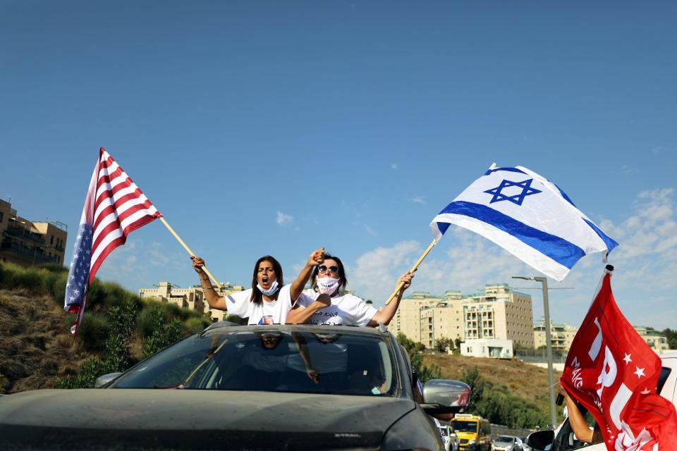 Women wave American and Israeli flags from a car window as they join a convoy to the U.S. Embassy in Jerusalem to show support for U.S. President Donald Trump, ahead of the upcoming U.S. election, in Jerusalem October 27, 2020.