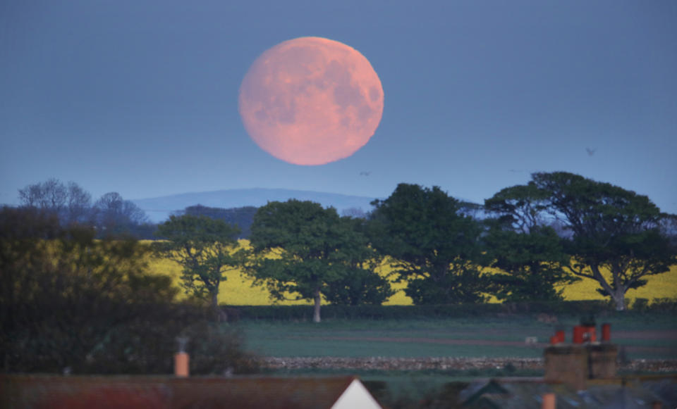 The moon sets over a house in Bamburgh, Northumberland, ahead of the final supermoon of the year.