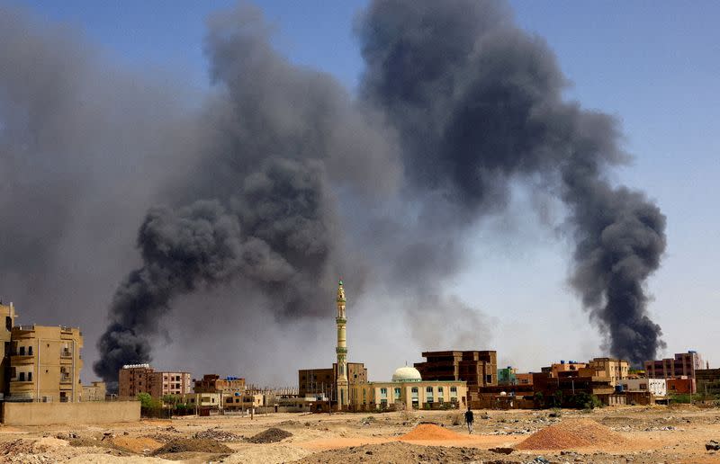 FILE PHOTO: Man walks while smoke rises above buildings after aerial bombardment in Khartoum North