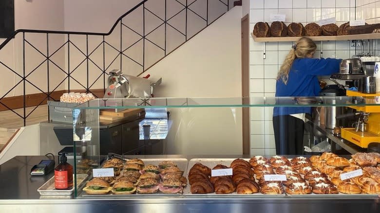 woman working behind pastry case with sandwhiches