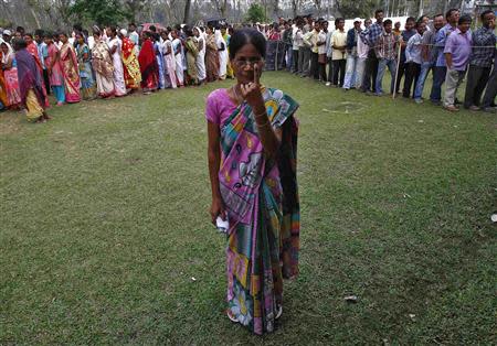 A woman shows her ink-marked finger after casting her vote as others line up to cast their ballot at a polling station in Nakhrai village in Tinsukia district in the northeastern Indian state of Assam April 7, 2014. REUTERS/Rupak De Chowdhuri