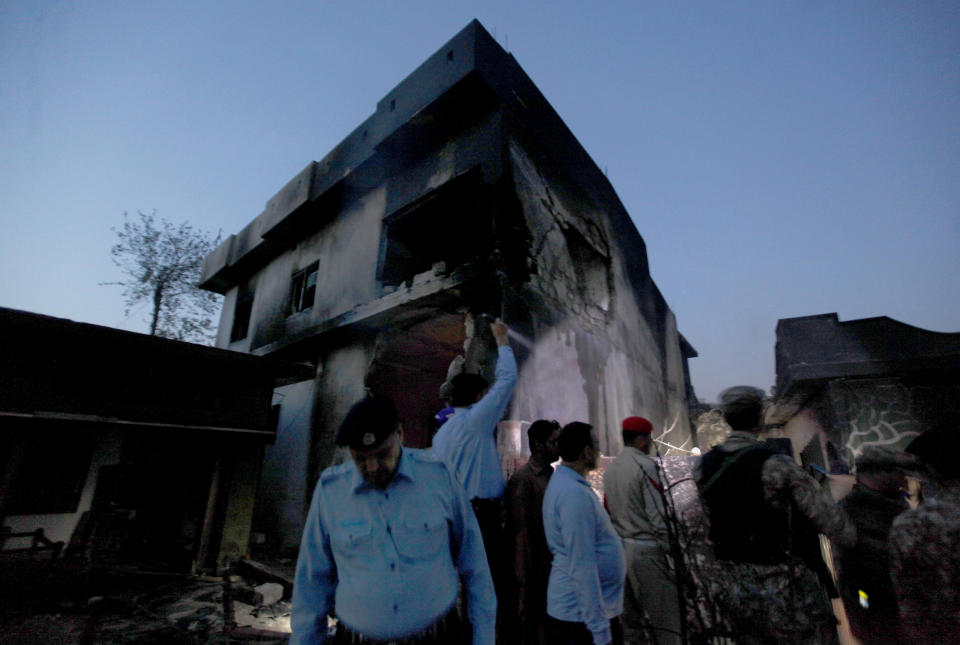 Pakistan army troops and police officers gather at the site of a plane crash in Rawalpindi, Pakistan, Tuesday, July 30, 2019. A small Pakistani military plane crashed into a residential area near the garrison city of Rawalpindi before dawn, killing some people, officials said. (AP Photo/Anjum Naveed)