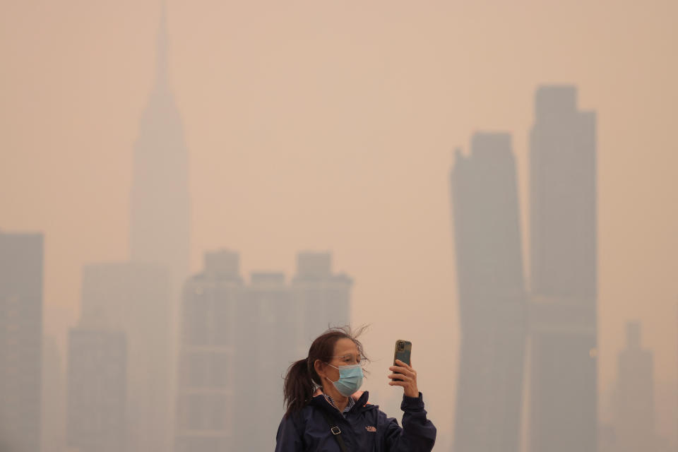 <p>A person wearing a mask uses a cell phone, as haze and smoke caused by wildfires in Canada hang over the Manhattan skyline, in New York City, New York, U.S., June 7, 2023. REUTERS/Andrew Kelly</p> 