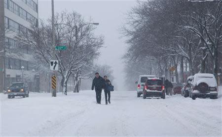 A couple make their way down a snow-covered street, as a winter storm moves across the midwest, in Milwaukee, Wisconsin December, 22, 2013. REUTERS/Darren Hauck