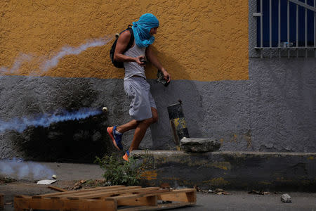 A demonstrator runs away from tear gas during a rally called by health care workers and opposition activists against Venezuela's President Nicolas Maduro in Caracas, Venezuela May 22, 2017. REUTERS/Carlos Barria