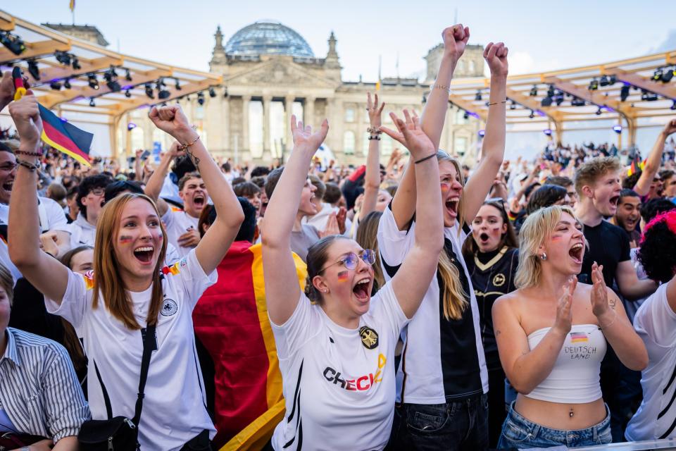 Deutschland-Fans jubeln beim Public Viewing in der Fanzone am Reichstagsgebäude als das 2:0 für Deutschland fällt. In der Mitte eine Frau mit Check24-Trikot. - Copyright: picture alliance/dpa | Christoph Soeder