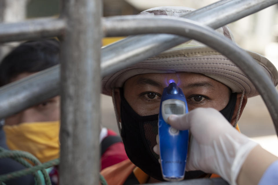 Un trabajador sanitario comprueba la temperatura corporal de un pasajero en un vehículo de transporte público en un control de salud en Bangkok, Tailandia, el jueves 26 de marzo de 2020. (AP Foto/Sakchai Lalit)