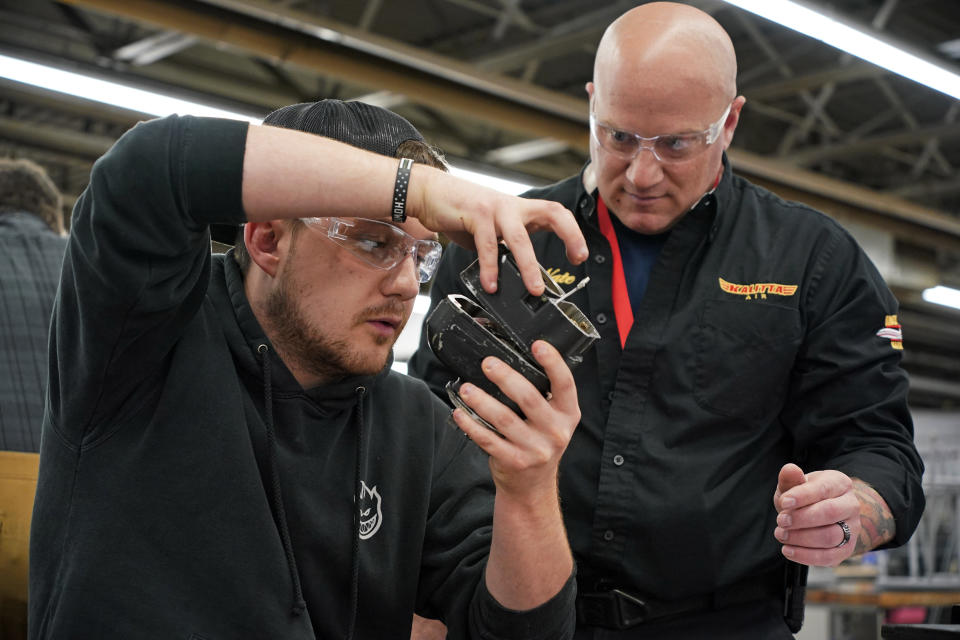 Steven Krasneski, left, a student at the Pittsburgh Institute of Aeronautics studies a portion of an aircraft engine with help from Kalitta Air's Nate Vincenty-Cole in West Mifflin, Pa., Tuesday, May 2, 2023. Students graduating from PIA have been awed by how much they're in demand. Recruiters are desperately seeking more aircraft mechanics for the airlines, airplane manufacturers, and repair shops that need them. (AP Photo/Gene J. Puskar)