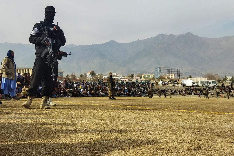 A Taliban security personnel stands guard as people attend to watch publicly flogging of women and men at a football stadium in Charikar city of Parwan province on December 8, 2022. / Credit: AFP via Getty Images