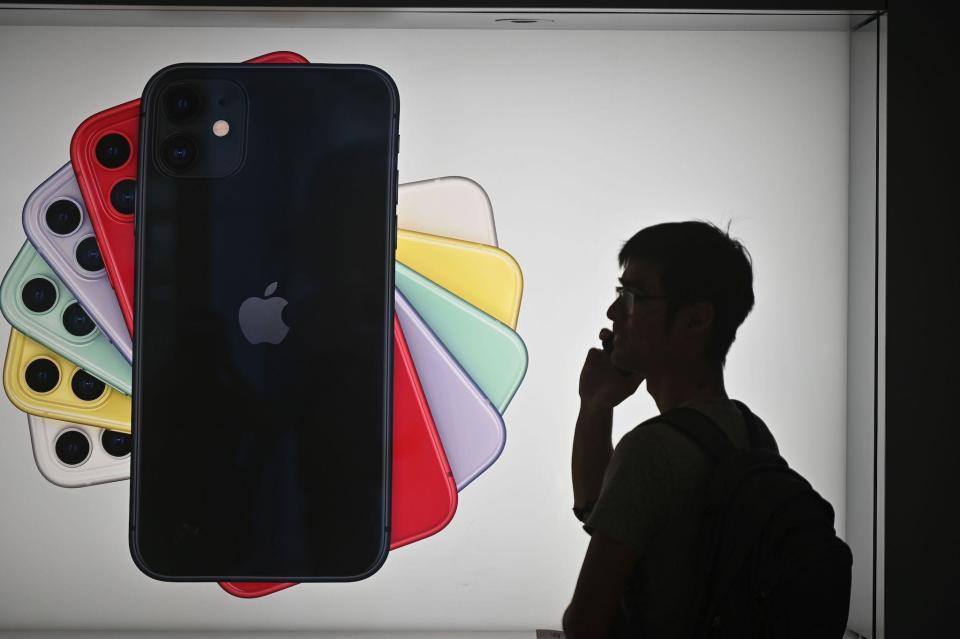 A man uses his mobile phone as he walks past advertising for the new iPhones outside the Apple store in Hong Kong on October 10, 2019: PHILIP FONG/AFP via Getty Images