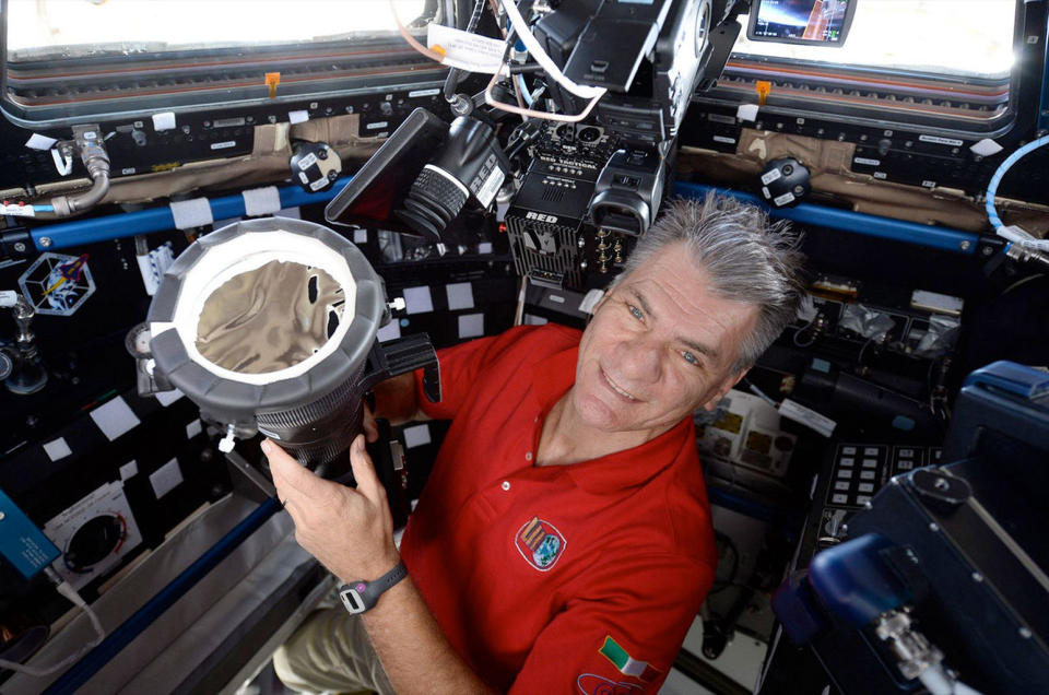 Expedition 52 flight engineer Paolo Nespoli of the European Space Agency (ESA) poses with his camera equipped with a 400mm lens and a solar filter in preparation to photograph the solar eclipse inside the Cupola on the International Space Station. <cite>NASA/ESA</cite>