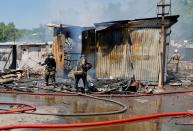 Firefighters extinguish a fire following recent shelling at a market in Donetsk