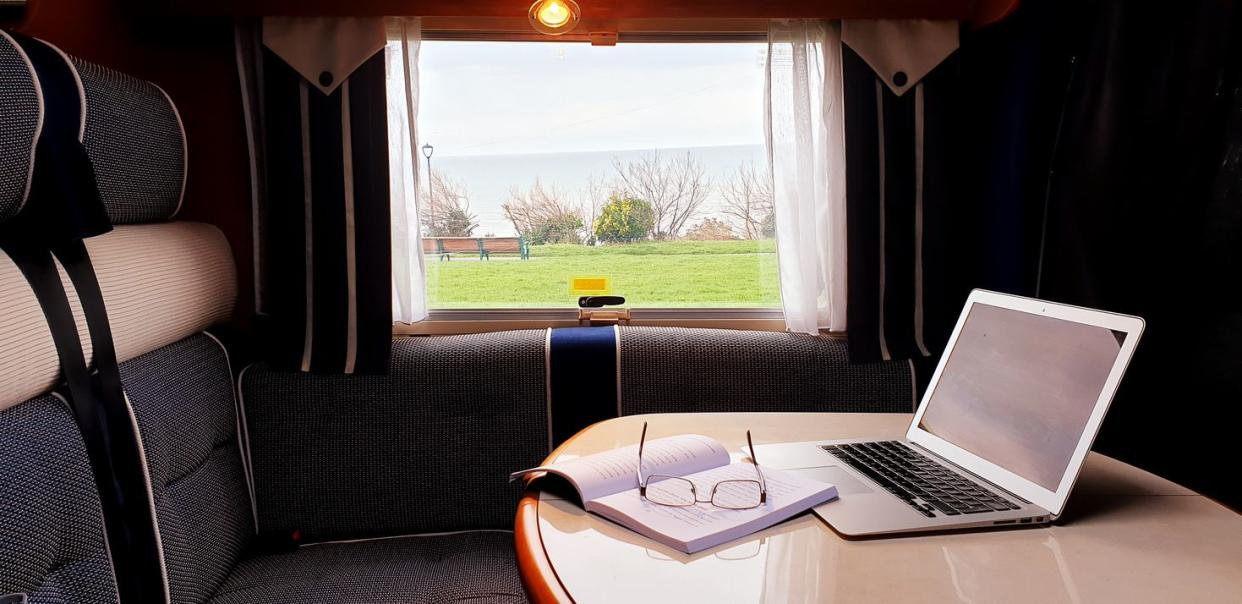 Living and working off-grid in a motorhome. RV mobile office with laptop, books, sea view