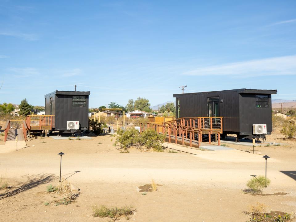 Black cabins with ramps in the desert.