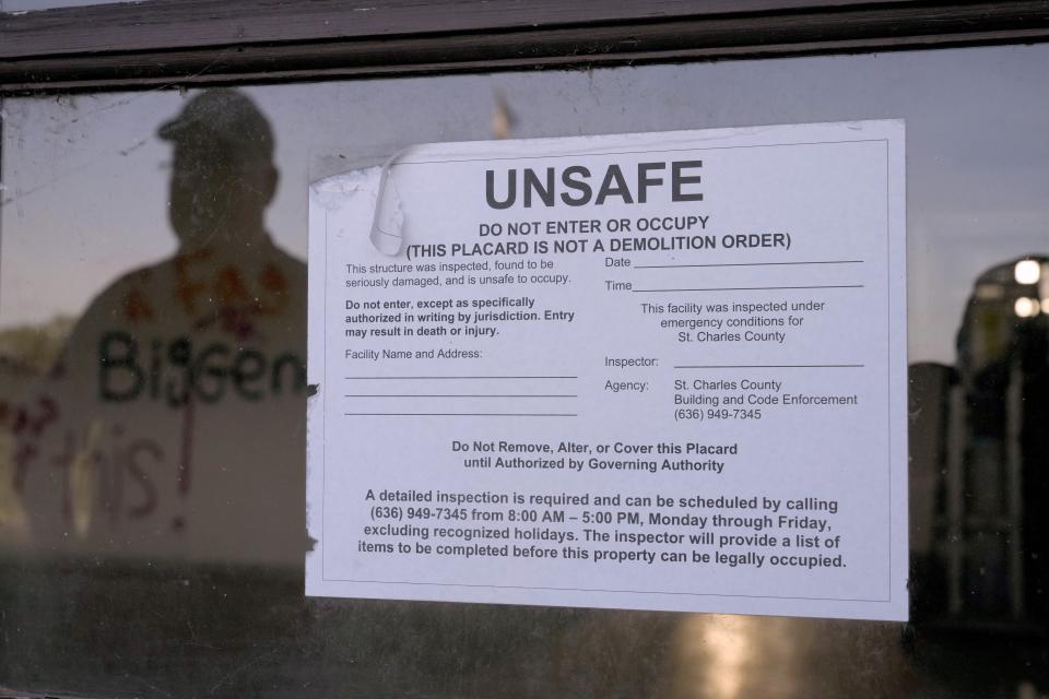 The reflection of West Alton Mayor Willie Richter is visible on a glass door outside a vacant and vandalized church Wednesday, May 22, 2024, in West Alton, Mo. Richter recalls the West Alton of decades ago: three churches, an ice cream shop, four taverns where people hung out. "Now we don't have any churches. We have one tavern that's open and it just got reopened not too long ago," he said. (AP Photo/Jeff Roberson)